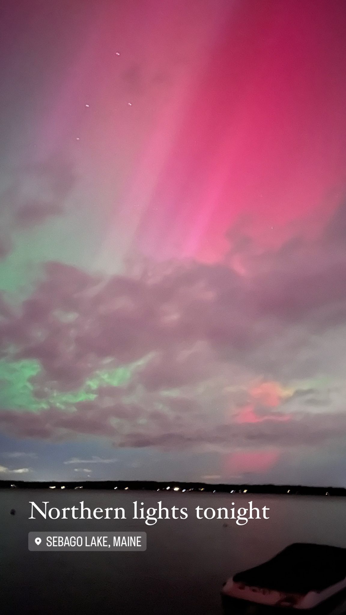 Northern lights glowing pink and green over Sebago Lake