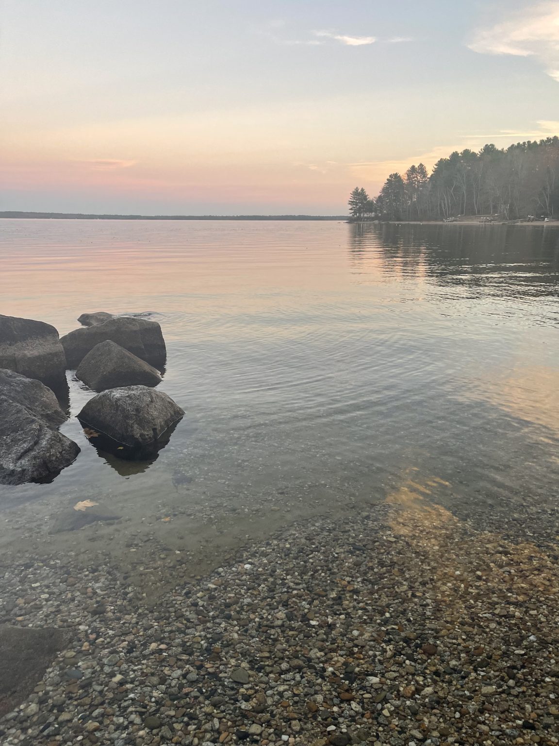 Clear shallow water and smooth rocks along the private beach at Sebago Retreat
