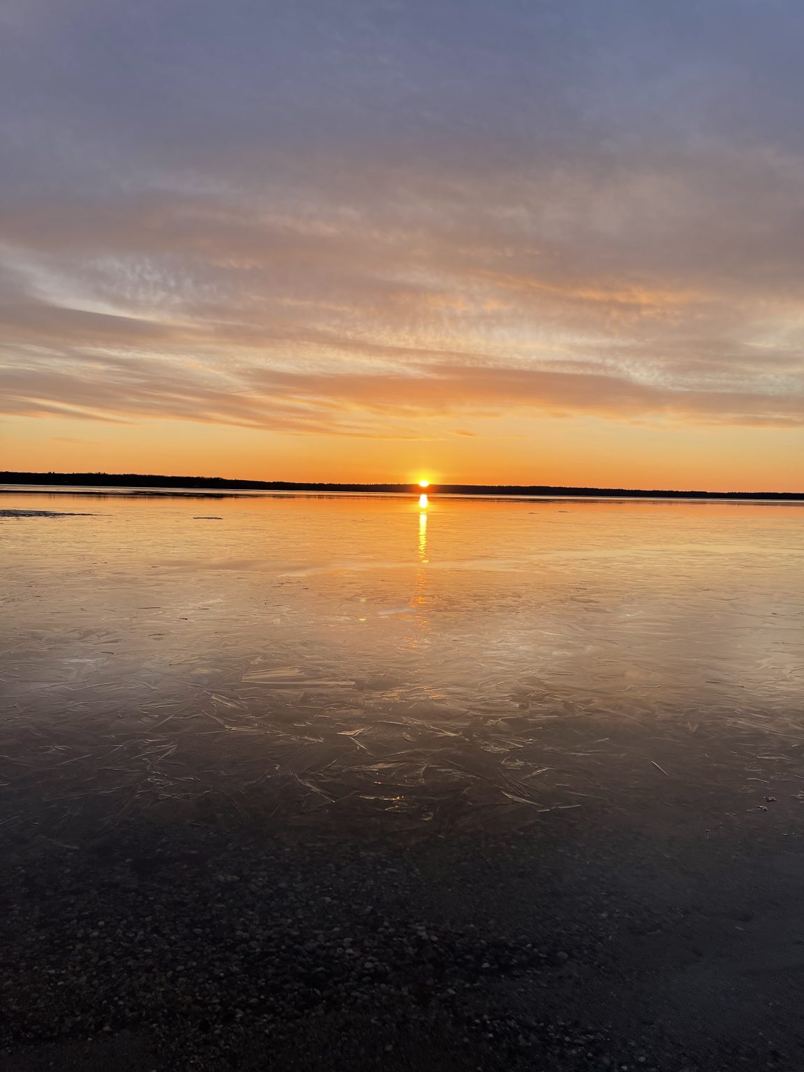 Golden sun path stretching across a calm Sebago Lake at sunset